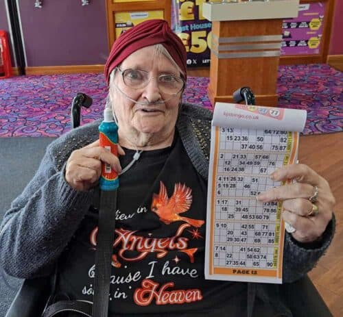 A woman holding a bingo card and dabber.